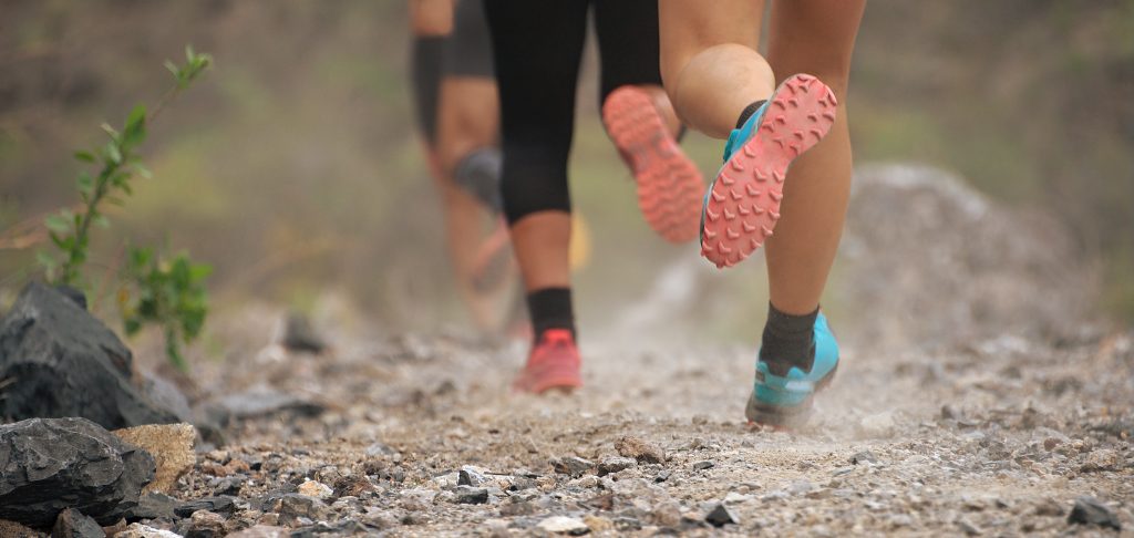 Trail running group on mountain path exercising, freeze action closeup of running shoes in action